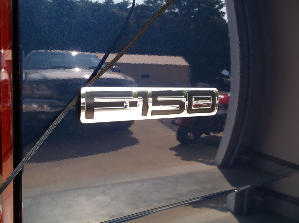 Chrome F-150 emblem on the side of a dark blue 2005 Ford F-150 truck