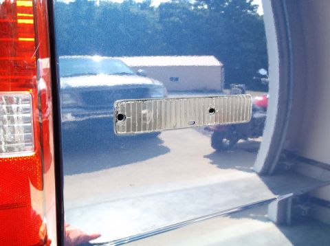 2005 Ford F-150 - Reflector removed from a blue Ford F-150 tailgate, showing reflections of other vehicles and structures.