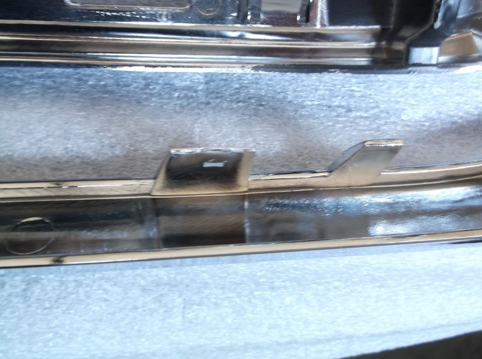 Close-up of a shiny chrome trim piece with mounting tabs