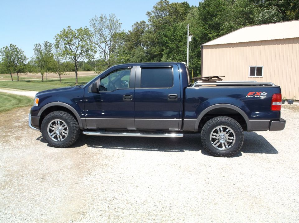 Dark blue Ford F-150 pickup truck with FX4 Off Road badging, chrome side steps, and aftermarket wheels