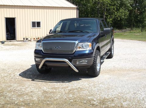 2005 Ford F-150 - This dark blue Ford F-150 pickup truck is viewed from a 3/4 front angle, parked on a gravel surface.