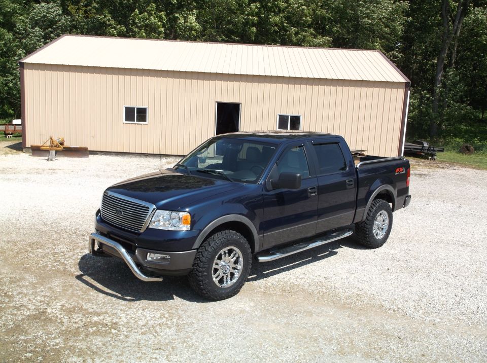 Dark blue Ford F-150 pickup truck parked in front of a tan metal building
