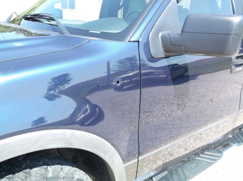2005 Ford F-150 - Side view of a blue 2005 Ford F-150 pickup truck, showing two small holes on the front fender.