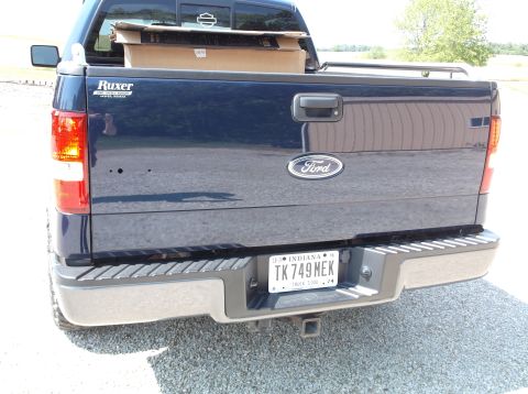 2005 Ford F-150 - The rear of a dark blue Ford F-150 pickup truck is shown, with a trailer hitch and an Indiana license plate.