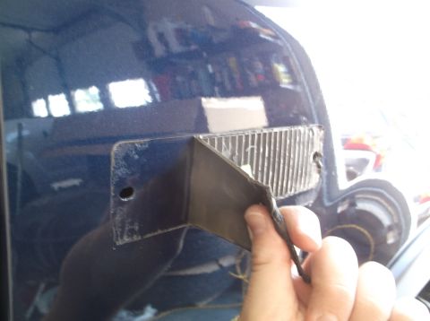2005 Ford F-150 - Close-up of a blue vehicle's fender showing the area where a license plate bracket was removed, revealing mounting holes.