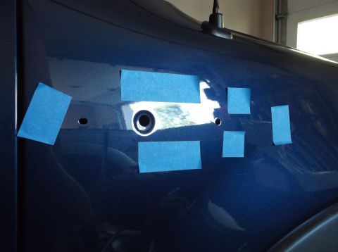 2005 Ford F-150 - Blue vehicle fender with blue masking tape applied around holes, possibly for a repair or modification.