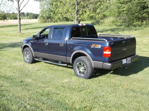 2005 Ford F-150 - This blue Ford F-150 pickup truck is parked on a grassy lawn with trees in the background.