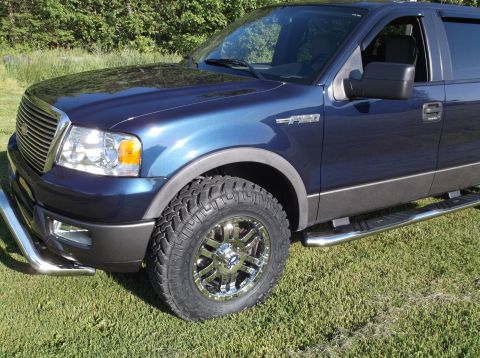 2005 Ford F-150 - This blue 2005 Ford F-150 pickup truck is shown from the front quarter angle, chrome wheels and running boards.