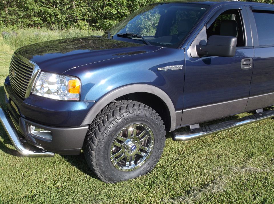 Blue 2005 Ford F-150 truck, front quarter view, chrome wheels, running boards