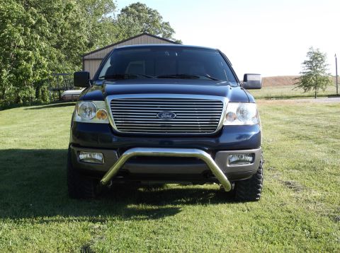 2005 Ford F-150 - A dark blue Ford F-150 truck is parked on a grassy lawn in front of a building.