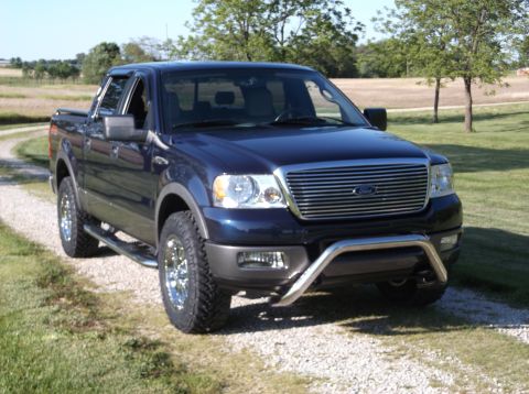 2005 Ford F-150 - This dark blue Ford F-150 pickup truck is viewed from a 3/4 front angle on a gravel driveway.