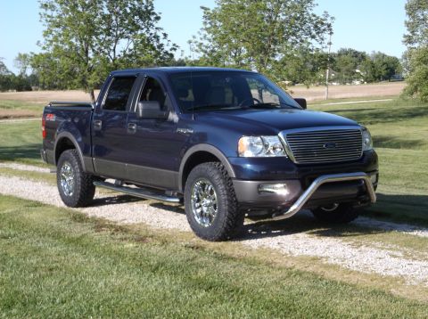 2005 Ford F-150 - This blue 2005 Ford F-150 pickup truck is shown from a three-quarter front view, a prominent chrome grille and a bull bar.