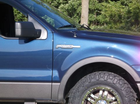 2005 Ford F-150 - The F-150 badge on the blue truck's fender indicates its model.
