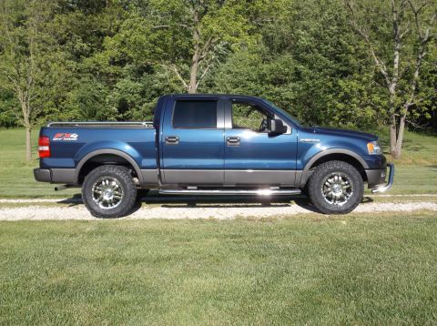 2005 Ford F-150 - Side view of a blue 2005 Ford F-150 pickup truck with aftermarket wheels and tires.