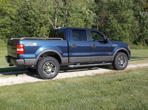 2005 Ford F-150 - This blue Ford F-150 SuperCrew pickup truck has aftermarket chrome wheels and side steps.