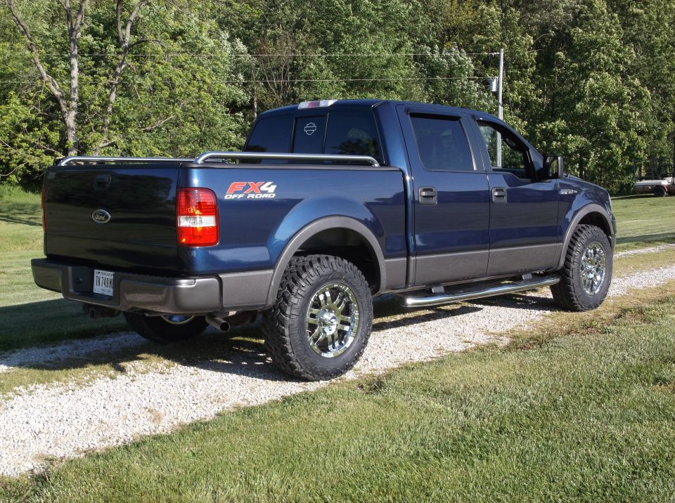 Blue Ford F-150 pickup truck parked on a gravel driveway