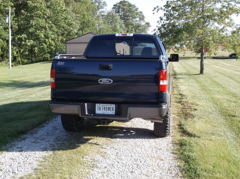 2005 Ford F-150 - Rear view of a dark blue 2005 Ford F-150 pickup truck parked on a gravel driveway.