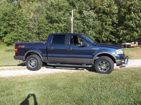 2005 Ford F-150 - This blue 2005 Ford F-150 FX4 pickup truck is shown from the side with aftermarket wheels and a bull bar.