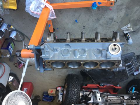 1987 Ford Bronco - Engine block undergoing rebuild, supported by an engine stand with a tire visible in the foreground.