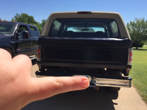 1994 Ford Bronco - The rear of a 1994 Ford Bronco is visible, parked beside a dark pickup truck on a sunny day.