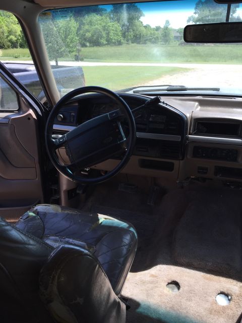 1994 Ford Bronco - The interior of an older model Ford truck shows a worn driver's seat and dashboard.
