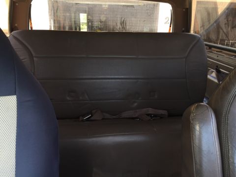 1994 Ford Bronco - The interior of a vehicle shows a rear bench seat with a seatbelt.