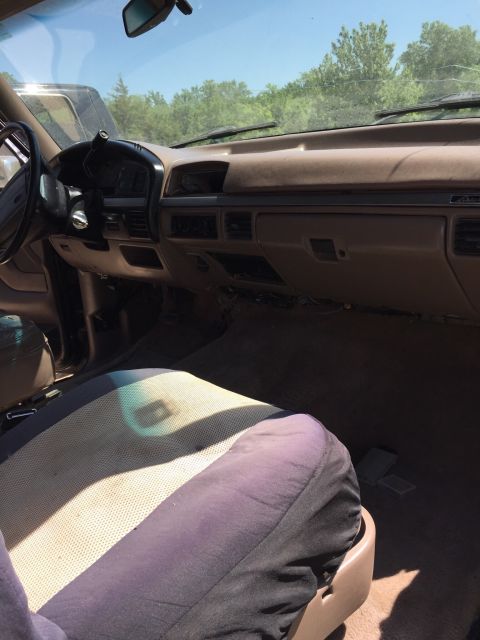 1994 Ford Bronco - The interior of a 1994 Ford Bronco, a brown dashboard and worn seats.