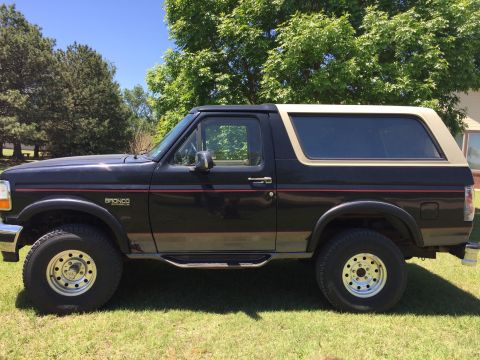 1994 Ford Bronco - This Ford Bronco is parked on a grassy lawn with trees in the background.