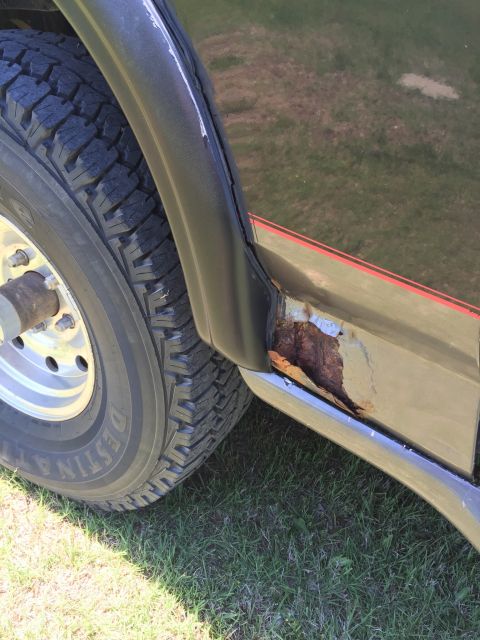 1994 Ford Bronco - The lower body panel of the vehicle shows significant rust damage near the rear wheel well.