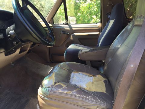 1994 Ford Bronco - The interior of the SUV shows significant wear on the seats and dashboard.