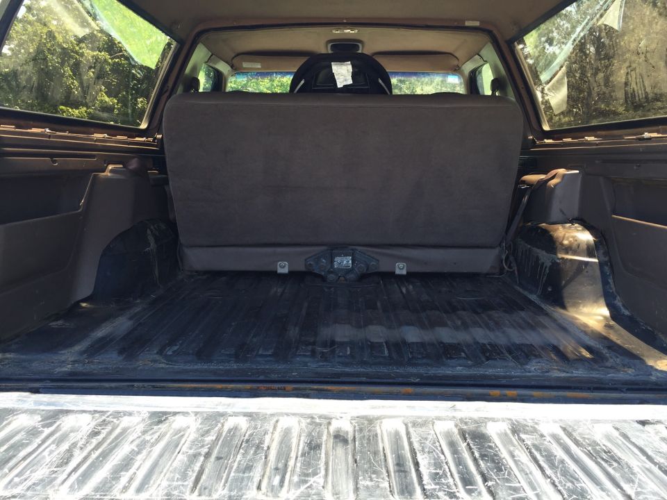 SUV cargo area with folded rear seats, tow hitch visible, trees outside