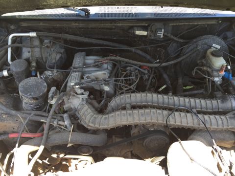 1994 Ford Bronco - The engine bay of a 1994 Ford Bronco shows its V8 engine, air intake system, and other mechanical components.