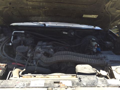 1994 Ford Bronco - The engine bay of a vehicle is shown with various hoses and components.