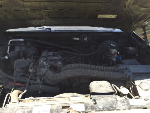 1994 Ford Bronco - The engine compartment of a vehicle is shown with various hoses and mechanical parts.