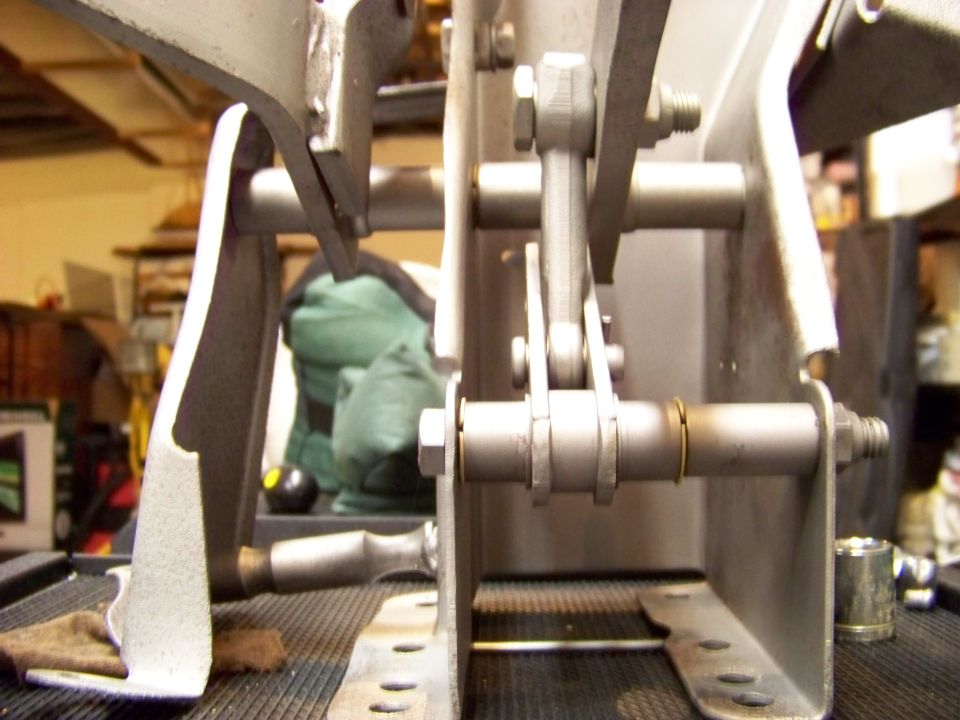Metal pedal assembly with linkages and bolts, viewed from the side