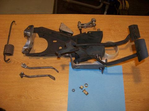 1974 Dodge Challenger - Disassembled vehicle pedal assembly components are arranged on a table, including pedals, springs, and small hardware.