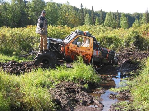 1985 Ford Bronco - This heavily modified truck is deep in the mud, with a person standing on its tire.