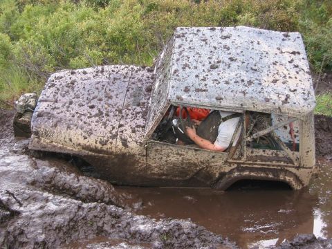 1985 Ford Bronco - This heavily mud-caked SUV appears to be stuck in a muddy mire.