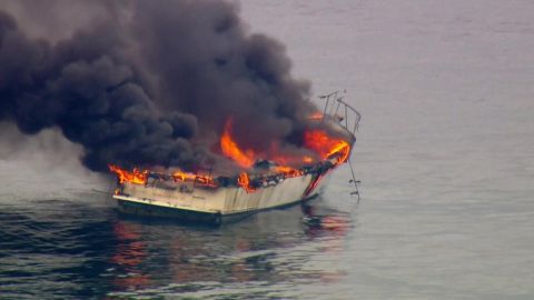 1991 Ford Bronco - A boat is on fire and emitting thick black smoke while floating on the water.