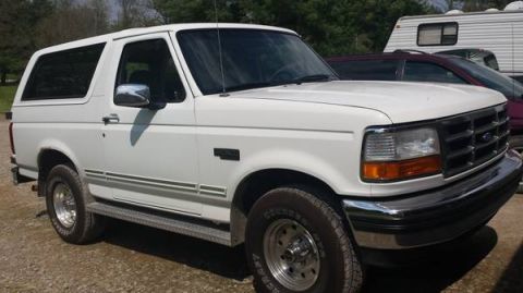 1995 Ford Bronco - This 1995 Ford Bronco is seen from a 3/4 front angle, with other vehicles and a trailer in the background.