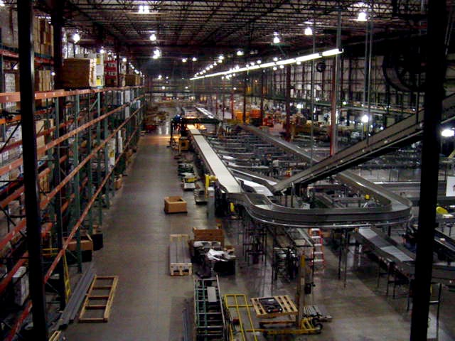 Warehouse interior with tall shelving units and a complex network of conveyor belts