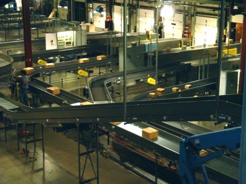 1979 Ford Bronco - A busy package sorting facility with multiple conveyor belts and boxes in motion.