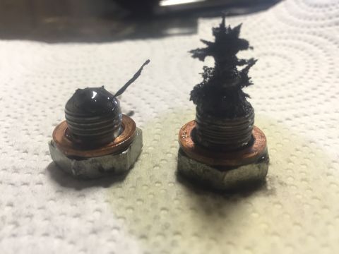1982 Ford Bronco - Two oil drain plugs show significant metal shavings, indicating potential engine wear or damage.