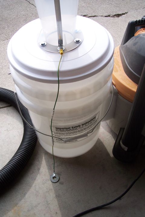 1990 Ford Bronco - A homemade dust collection system is set up with a bucket, hose, and shop vac on a concrete surface.