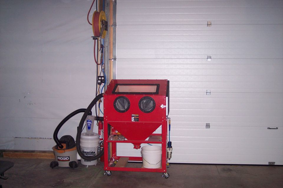 Red sandblaster cabinet with vacuum and hose
