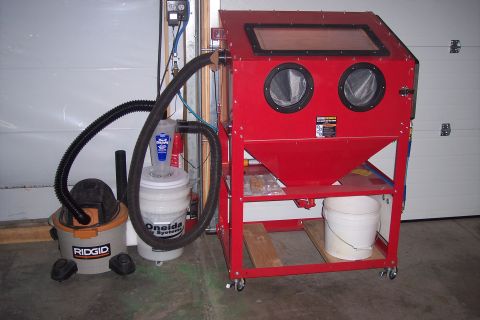1990 Ford Bronco - A red sandblaster cabinet is set up with a shop vac and dust collector in a garage.