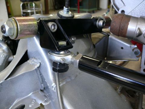 Close-up of a black metal bracket attached to a silver suspension component with a threaded rod