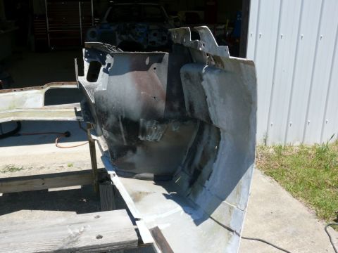 Car body section, possibly front end, on wooden sawhorses. Another car body is visible in the background