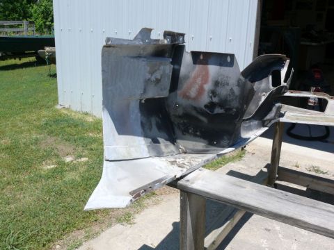 Car body panel on sawhorses outside a building. Supermotors.net logo visible