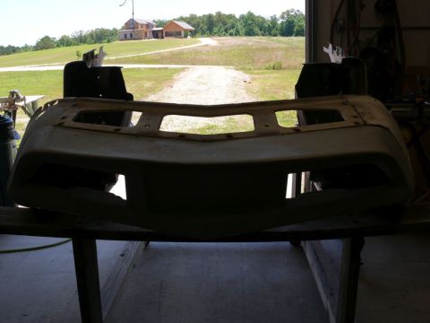 Car bumper with rectangular cutouts, resting on sawhorses indoors